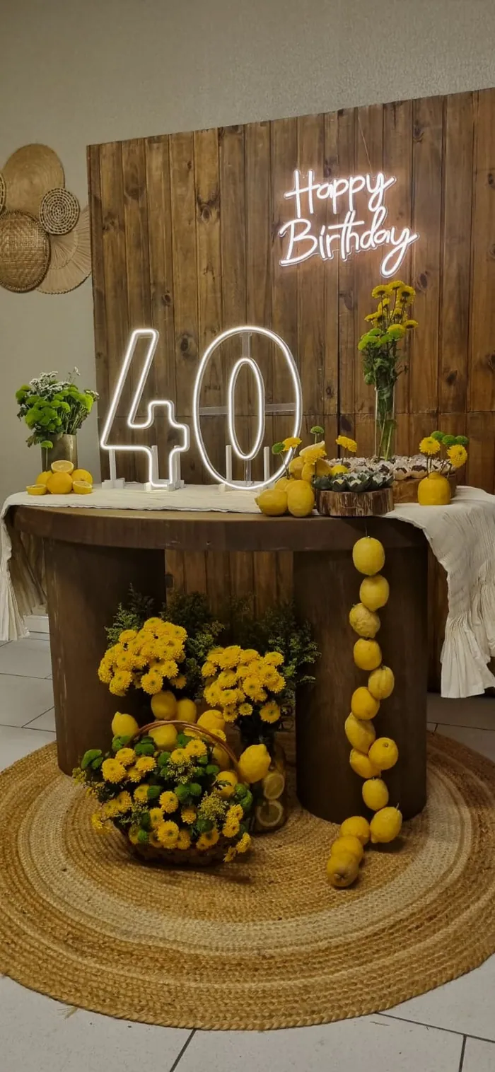 Detalhe de uma comemoração no Bangu com painel de madeira, flores e letreiro Happy Birthday