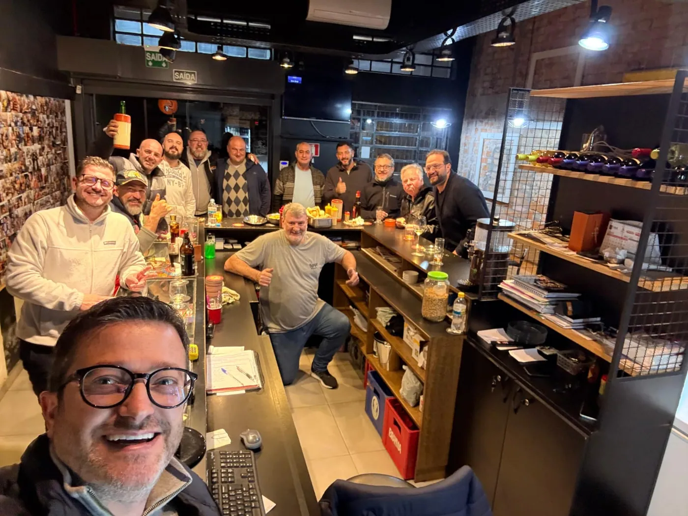Grupo de amigos sorrindo em uma foto junto ao balcão do Bangu